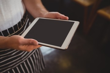 Midsection of waiter holding tablet