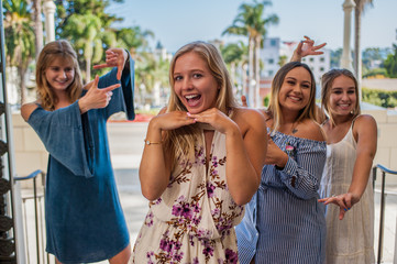 Pretty college girls together in a group making silly faces behind blond in front.