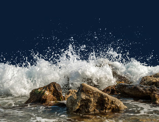Fototapeta premium Splashing sea water on rocks isolated on a dark blue background