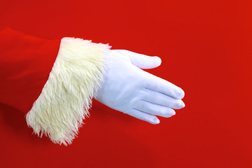 Santa Claus hand presenting your christmas text or product over red background with copy space