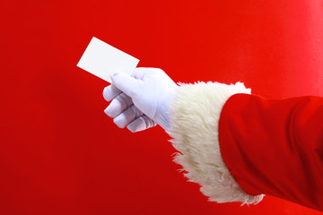 Santa Claus hand presenting your christmas text or product over red background with copy space