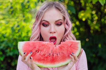 Beautiful young woman with pink hair enjoying watermelon