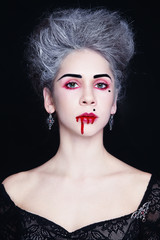 Portrait of young beautiful stylish gothic woman with vintage hairdo and bloody mouth