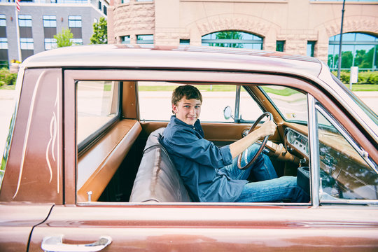 Happy young Caucasian teenage boy driving car
