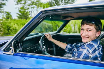 Cheerful young Caucasian man sitting in his car