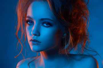 Portrait of beautiful girl in blue light and red light close up with hairstyle