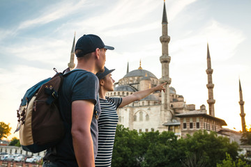 Naklejka premium A pair of travelers near the world-famous Blue Mosque in Istanbul, Turkey. The girl shows direction.