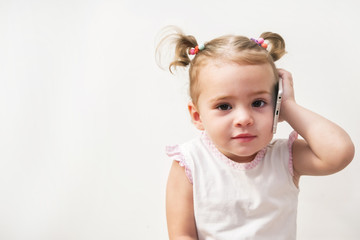 Baby girl speaking by cell phone, white background