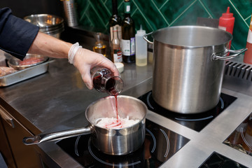 Chef is adding red wine to a dish