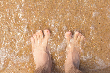 Foot on the sand. Transparent, clean water passes over your feet.