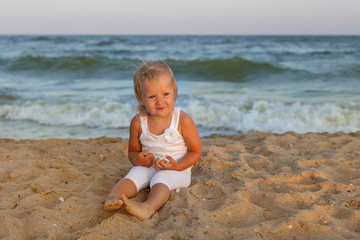 Cute baby girl sitting on the seashore