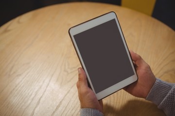 Cropped hand of man holding tablet at table