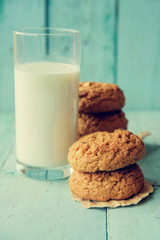 A plate of peanut butter oatmeal cookies served with a cold glass of milk. These cookies are completely vegan and the milk is almond milk.