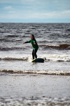 Young little girl on beach taking surfing lessons