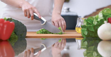 Close-up of four human hands are cooking in a kitchen. Friends having fun while preparing fresh salad. Vegetarian, healthy meal and friendship concept