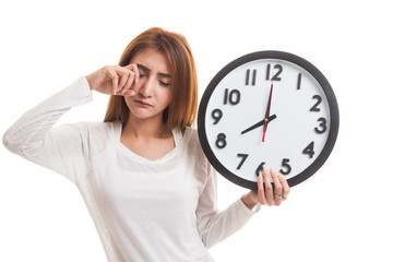 Sleepy young Asian woman with a clock in the morning.