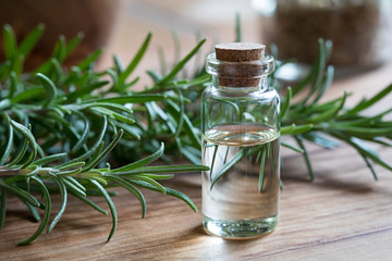 A bottle of rosemary essential oil with fresh rosemary twigs