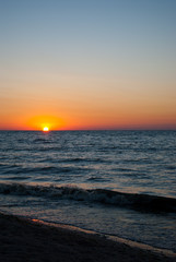 Beautiful sunrise over the sea, orange red sun, purple blue and pink sky without clouds, blue sea, sand wave vacation