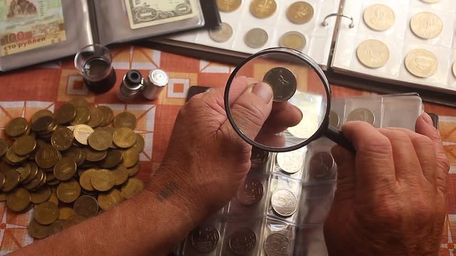 Page of numismatics album with different coins isolated. Coin album collection from different countries. Consider coins under a magnifying glass. Hobby collecting coins.