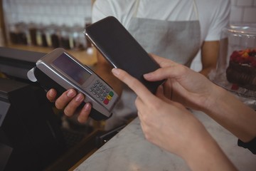 Cropped hand of customer making contactless payment with waiter