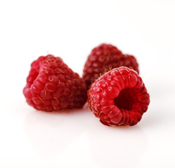Close-up of three raspberry berries on white background.