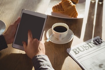 Cropped hands of businessman using tablet in cafe