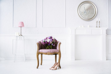 Bright white interior with lots of pink and pirple flowers on chair on wooden floor