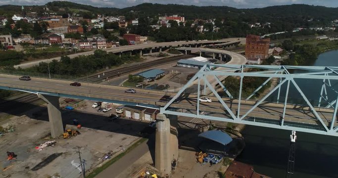 A high angle rising aerial establishing shot of traffic passing on the Rochester Monaca Bridge over the Ohio River in Western Pennsylvania.  	