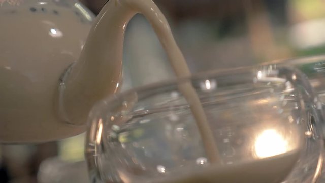 Close-up shot of serving masala tea in the restaurant. Pouring Indian hot drink into a glass tea bowl