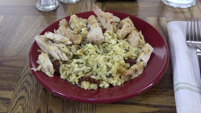 Serving a plate of greek style chicken on orzo rice