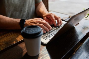 man typing at computer with coffee in foreground