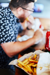 close up of fries in a basket man in background eating