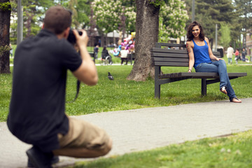 Boy taking a photo of a girlfriend in park