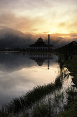 Naklejka premium Beautiful morning near the lake, fog cover the hill, reflection and lightiing from the mosque