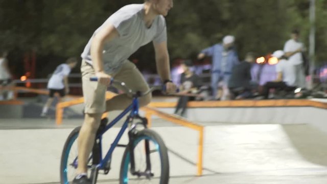 MTB bicycle rider does various tricks while riding in skatepark . Extreme Sports, rider does barspin to three sixty trick at night 