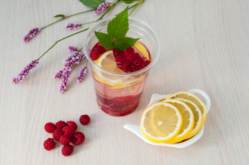 Still life: water with lemon and raspberries, wild flowers