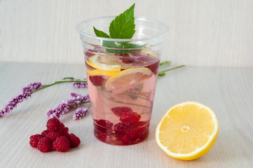 Still life: water with lemon and raspberries, wild flowers