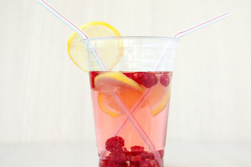 Straws in a drink made of lemon with raspberries