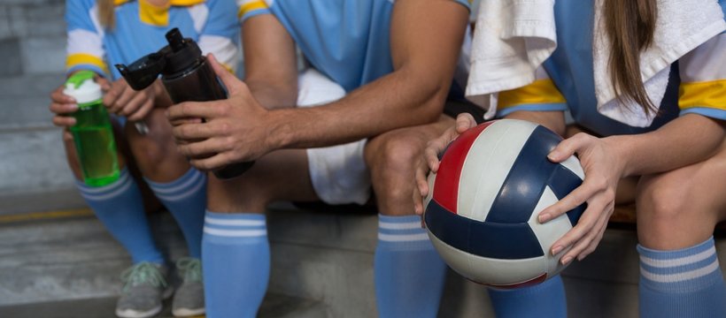 Mid Section Of Sports Team Holding Volleyball