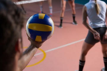 Cropped hand of player holding volleyball by female teammate