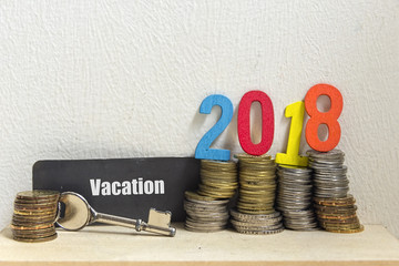 Key and coin with the word VACATION and Number 2018 - the concept of savings