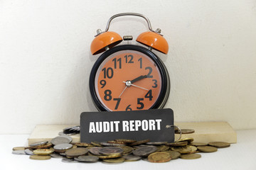 Alarm clock and coins the word "AUDIT REPORT" - business concept