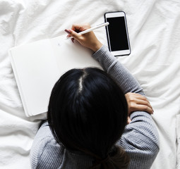 Woman is using mobile on the bed