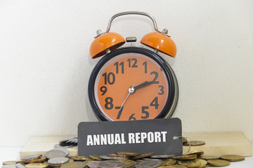 Alarm clock and coins the word "annual report" - business concept