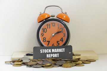 Alarm clock and coins the word "STOCK MARKET REPORT" - business concept