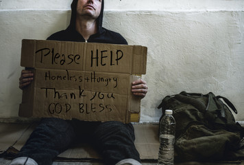 Homeless man holding helping board on the street 