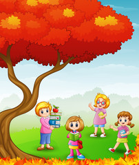 Obraz na płótnie Canvas Happy children studying in the autumn trees