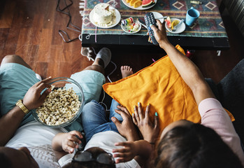 Black family eating popcorn while watching movie at home