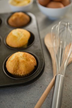 High angle view of muffins in tin by wire whisk