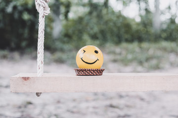 Smiley face yellow ball on a swing in the garden -vintage filter added